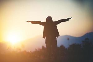 Silhouette einer Frau, die über schönen Himmelhintergrund betet foto