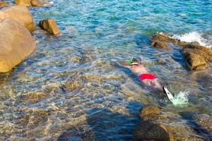 Junger Mann, der in klarem, tropischem, türkisfarbenem Wasser schnorchelt foto