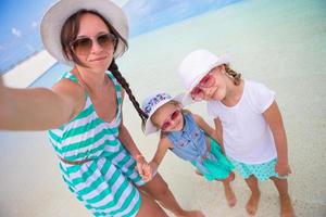 mutter und kleine mädchen, die selfie am tropischen strand machen foto