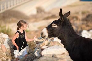 kleines entzückendes mädchen mit esel auf mykonos foto