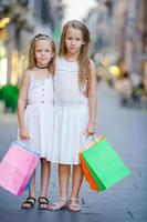 hübsche lächelnde kleine Mädchen mit Einkaufstüten foto