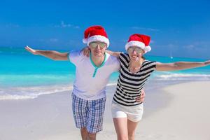 Porträt des jungen Paares in den Weihnachtsmützen genießen Strandurlaub foto