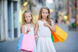 hübsche lächelnde kleine Mädchen mit Einkaufstüten foto