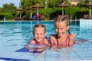 entzückende glückliche kleine mädchen, die spaß im schwimmbad haben foto