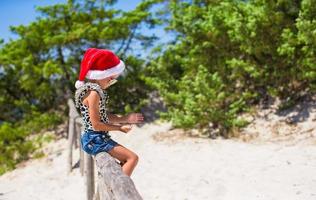 süßes kleines mädchen in weihnachtsmütze während des strandurlaubs foto