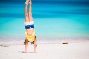 Entzückendes aktives kleines Mädchen am Strand während der Sommerferien foto