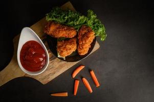 knusprig gebratenes Hähnchen und Karottenstangen mit Sauce foto