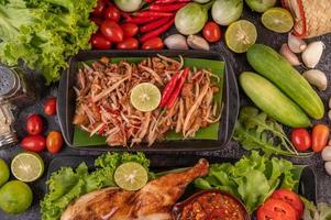 thailändischer Papayasalat, umgeben von Gemüse und Hühnchen