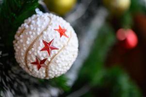 Nahaufnahme einer weißen Kugel, die vom Weihnachtsbaum hängt