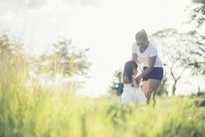 Mutter und kleine Tochter spielen zusammen auf einer Wiese foto