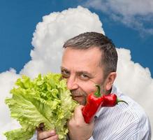 Mann hält Salat gegen den blauen Himmel foto