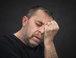 Kopfschmerzen. Mann mit Gesicht von Hand geschlossen foto