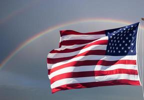 amerikanische Flagge gegen einen bewölkten Himmel mit einem Regenbogen foto
