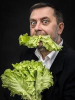 Mann, der Salat hält und isst foto