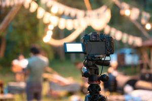 Kameraaufnahme auf Stativ mit defokussierter beleuchteter Live-Musik-Konzertveranstaltung und Camping foto