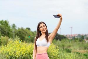 schöne junge frau, die im stadtrennen läuft und ein selfie macht, junge frau, die selfie macht, während sie fitnessübungen macht