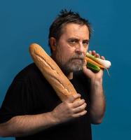Mann hält Gemüse in der einen Hand und Brot in der anderen foto