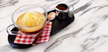 Affogato-Kaffee-Dessert, Tasse Vanilleeis mit Espresso und Teelöffel auf rot karierter Baumwolle mit rostfreiem Fahndungsfoto in schwarzem Tablett auf weißem Marmortisch mit Kopienraum-Erfrischungsgetränk foto