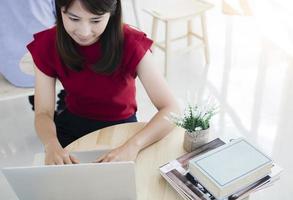 junge asiatische hübsche studentin benutzt laptop im café, um informationen zu suchen und zu lernen