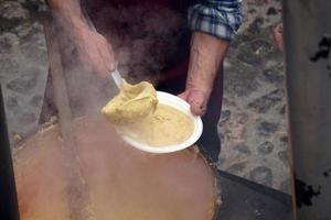 leute, die polenta traditionelles maisweizenmehl kochen foto