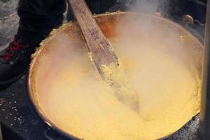 Rango, italien - 8. dezember 2017 - leute, die polenta traditionelles maisweizenmehl kochen foto