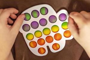 pop it ist ein buntes Anti-Stress-Spielzeug in Kinderhänden. Blasenspiel. Anti-Stress-Spielzeug. foto