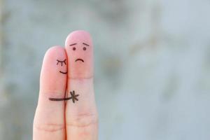 Fingerkunst eines unzufriedenen Paares. Mann ist traurig, Frau beruhigt sie. sie küsst und umarmt ihn. foto
