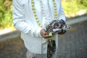 bräutigam im weißen hochzeitskleid, das traditionellen kopfschmuck hält foto