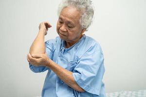 asiatische senior oder ältere alte damenpatientin fühlen sich schmerzen im ellbogen auf dem bett in der krankenhausstation, gesundes starkes medizinisches konzept. foto