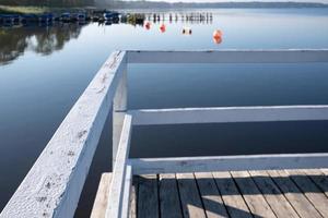 Holzsteg mit Geländer gegen Absturz ins Wasser vor der Kulisse eines Sees. foto