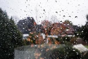 Regentropfen auf dem Fensterglas draußen vor dem Hintergrund des Hofes. Platz kopieren.