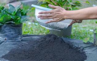 Zubereitung der Bodenmischung aus fruchtbarem Kompost, Humus und Vermiculit auf schwarzem Müllbeutelboden im Garten. Mischen der Bodenkomponenten zur Vorbereitung des Substrats zum Umpflanzen von Pflanzen. foto