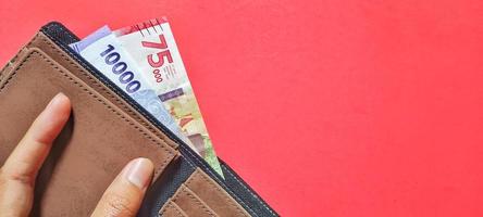 Indonesische Rupiah-Banknoten neue Emission 2022 in einer Brieftasche isoliert auf rotem Hintergrund. foto