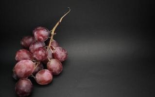 frische trauben, die gerade aus dem weinberg gepflückt wurden, negativer raum und isoliert auf schwarzem hintergrund. foto