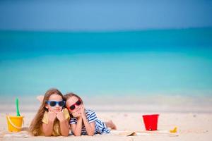 Kleine Mädchen, die während des tropischen Urlaubs mit Strandspielzeug spielen foto