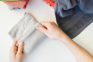 Die Hand einer Frau hält ein Frotteehandtuch aus einem Kleiderkorb. Handtuch nach dem Waschen. das mädchen faltet das handtuch nach dem waschen und faltet kleidung. foto