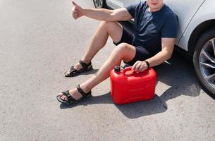 der fahrer will in einen leeren autotank tanken, einen leeren roten kanister am straßenrand. hält auf der Straße. Kraftstoffproblem, höhere Gewalt. foto