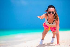 Fitness junge Frau macht Liegestütze am Strand foto