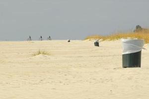 drei mülleimer und drei radfahrer am atlantikküstensand von hilton head island, south carolina. foto