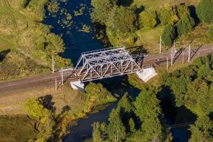 Luftpanoramablick auf die Stahlrahmenkonstruktion einer riesigen Eisenbahnbrücke über den Fluss foto