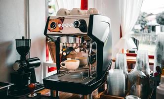 Kaffeeextraktion aus der Kaffeemaschine mit einem Siebträger, der Kaffee in eine Tasse gießt, Espresso aus der Kaffeemaschine im Café