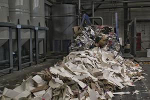 Schreddern von Altpapier-Förderbändern zum Recycling von Verpackungen, Müll und Pappe gegen Ballen gebrauchter Kartons, die zur Wiederverwendung in Industrieanlagen gesammelt wurden. Zero Waste, umweltfreundliches Konzept foto