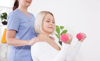 Bild einer Frau mittleren Alters während der Rehabilitation in einer professionellen Klinik. Rehabilitation, Physiotherapie mit Hanteln foto