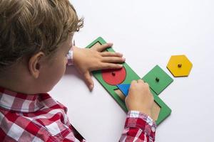 das untergeordnete Element sammelt den Sortiererkonstruktor. Puzzle Sorter, ein frühes Entwicklungskonzept. Kinderhände legen das Puzzle foto