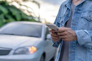 Sicherheit im Notfall. Mann wählt wegen einer Autopanne im Wald ein Handy für eine Notrufnummer. Die Wartung des Autos vor der Fahrt erhöht die Unfallsicherheit. foto