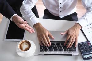 die menschliche hand benutzt die tastatur neben dem notizbuch auf dem schreibtisch. internetbildungs- und kommunikationskonzepte foto