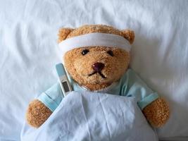 Teddybär und Bandage mit Thermometer. Krankheits- und Verletzungskonzept foto