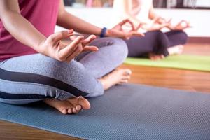 Nahaufnahme einer Frau, die Yoga in einer Meditationsposition im Fitnessstudio macht. konzept des übens von ruhe oder frieden und entspannung. Übung für die Gesundheit des Körpers und die geistige Gesundheit. foto