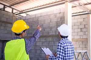 Ingenieure oder Architekten besprechen mit Kunden oder Auftragnehmern die Details zur Befestigung der Dachkonstruktion des Hauses. Inspektion und Beratung für qualitativ hochwertige Arbeit.