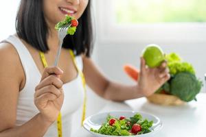 Schöne asiatische Frauen essen gerne Salat, um Gewicht zu verlieren. gesunde junge Frau, die Gemüsesalat isst. diät, gesunde lebensmittelkonzepte. foto